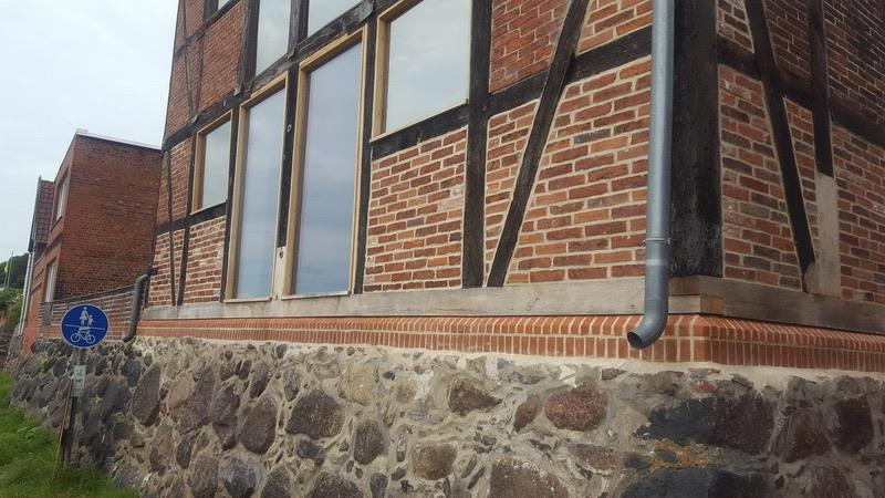 Hausecke eines Fachwerkgebäudes mit instand gesetztem Feldsteinsockel