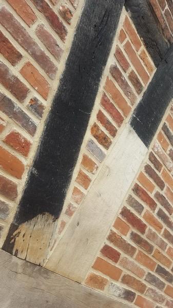Detail eines Fachwerkbalkens mit ausgebessertem Balkenfuß und Ziegelausfachung