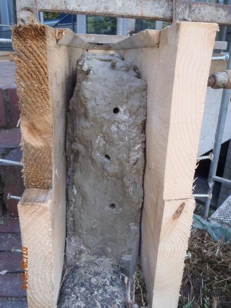 Betonstütze mit Holzschalung während der Reprofilierung mit Reparaturmörtel