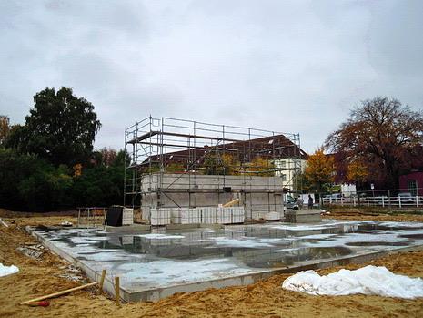 Streifenfundamente eines Anbaus, im Hintergrund das eingerüstete Bestandsgebäude