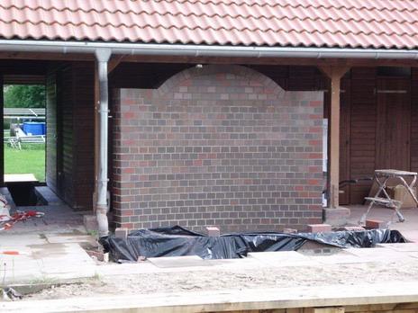 Gemauerte Rückwand mit Bogen unter einer Terrassenüberdachung, im Bau