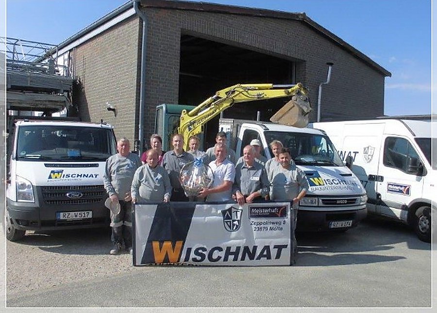 Die Mannschaft der Markus Wischnat Bauunternehmen GmbH vor den Firmenfahrzeugen und dem Bagger am Betriebshof in Mölln