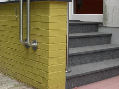 Granittreppe an gelb gestrichenem Klinkermauerwerk mit Handlauf